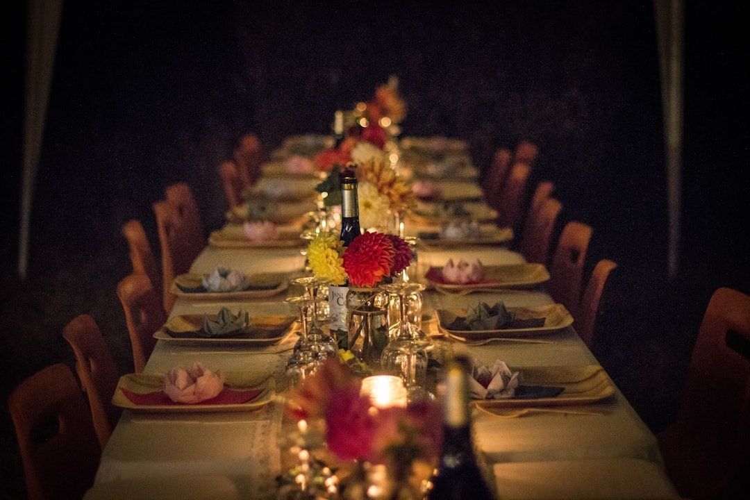 Långt festbord med blommor, vinflaskor och levande ljus